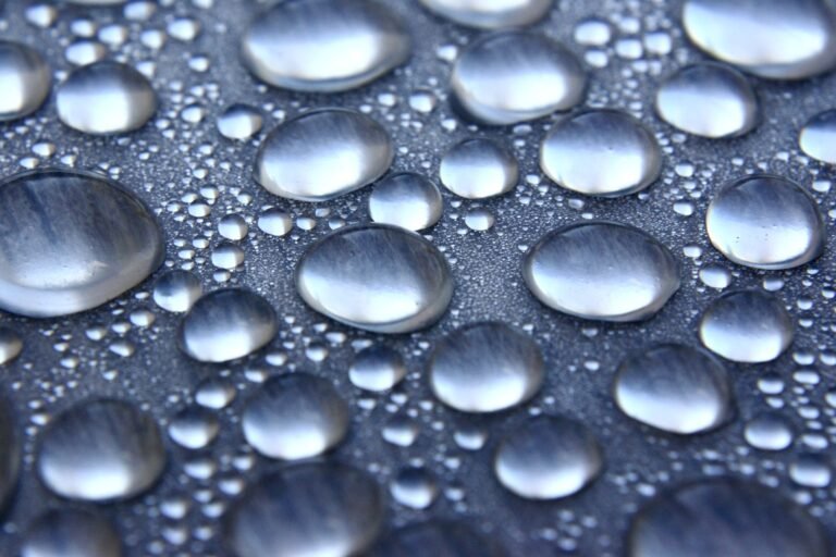 Close-up macro of clear water droplets on a smooth surface in soft natural light