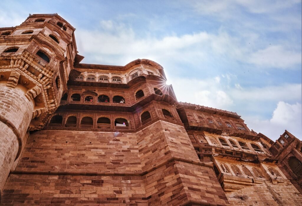 The red sandstone walls of Mehrangarh Fort in Jodhpur under a blazing sun and harsh, clear Indian daylight.