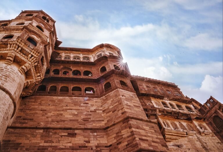 The red sandstone walls of Mehrangarh Fort in Jodhpur under a blazing sun and harsh, clear Indian daylight.