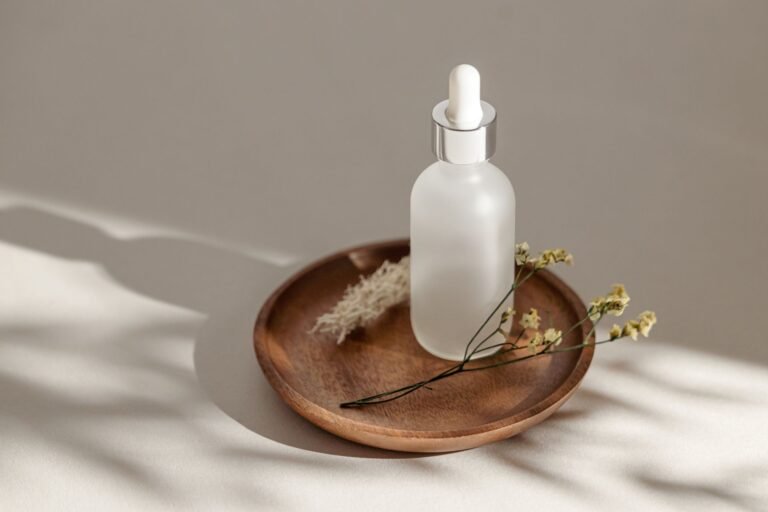 A frosted skincare dropper bottle on a wooden dish in soft daylight
