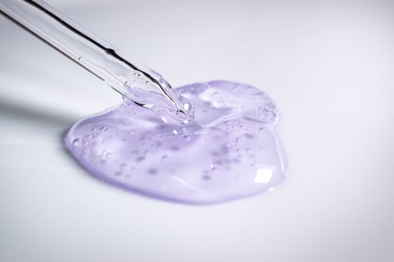 A pipette dispensing a clear cosmetic gel onto a smooth surface