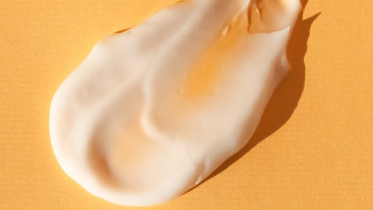 Sunscreen cream texture on a bright yellow surface