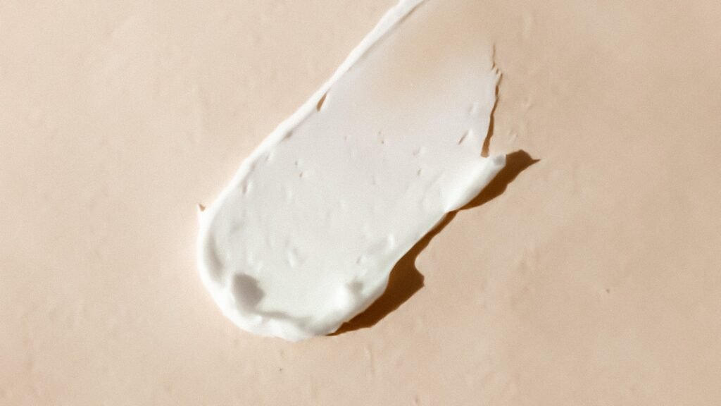 White sunscreen cream smeared on a beige surface